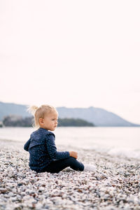 Portrait of boy sitting on rock at beach