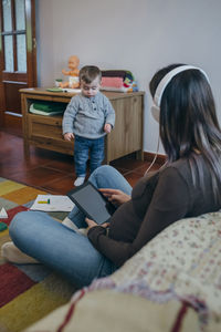 Mother using digital tablet while son standing by table at home