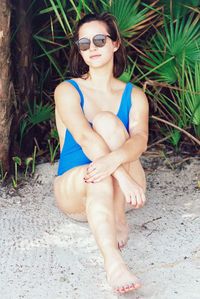 Portrait of beautiful woman sitting on sand at beach