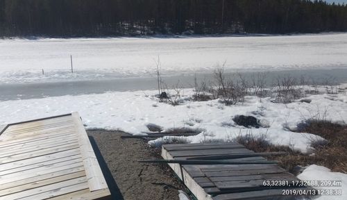 Snow on land by frozen lake