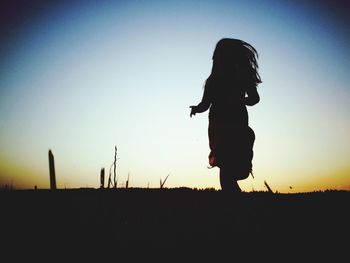 Silhouette of woman standing on landscape at sunset