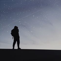 Rear view of silhouette man standing against star field