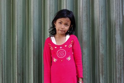 Portrait of smiling girl standing against wall