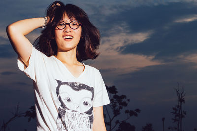 Portrait of smiling young woman standing against sky