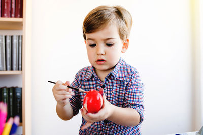 Cute boy painting easter egg at home