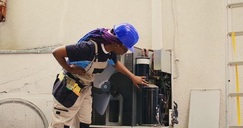 Side view of man using mobile phone while standing against wall