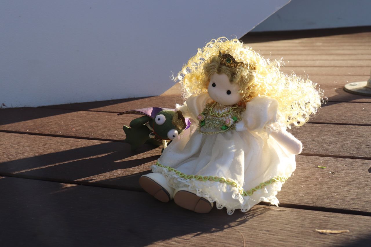 toy, sunlight, shadow, childhood, white, nature, doll, representation, wood, day, one person, yellow, child, women, dress, human representation, celebration, sunny, blue, outdoors, flower, full length, clothing, female, flooring