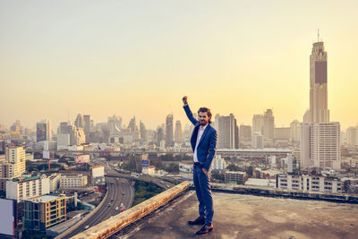 Businessman standing over cityscape during sunset