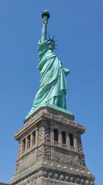 Low angle view of statue of liberty against blue sky