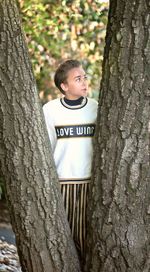 Portrait of girl standing on tree trunk