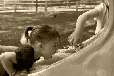 Side view of girl drinking water at fountain