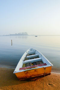 Boat moored on lakeshore against clear sky