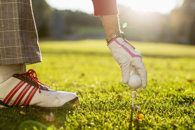 Cropped image of senior woman placing golf ball on tee