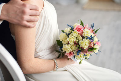 Midsection of bride holding bouquet