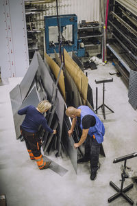High angle view of male and female carpenters working together in workshop