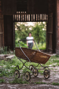 Wheelbarrow on field with woman standing in background