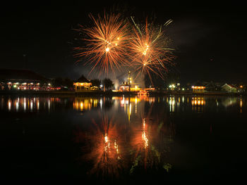 Firework display over river against sky at night