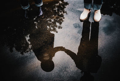 Low section of person standing by puddle on street