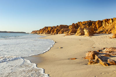 Rocks on beach against clear sky