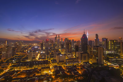 Illuminated cityscape against sky during sunset