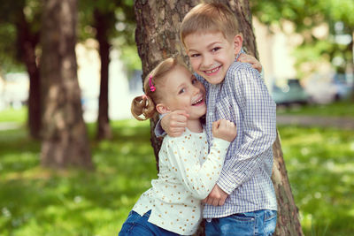 Portrait of smiling sibling embracing while standing at park