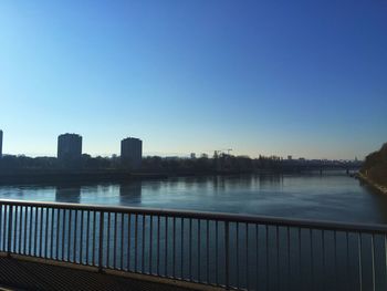 Scenic view of river by buildings against clear blue sky