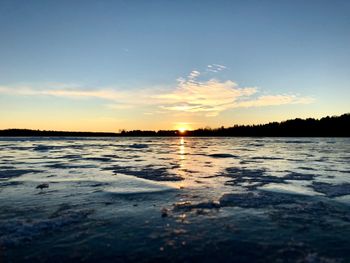 Surface level of beach against sky during sunset
