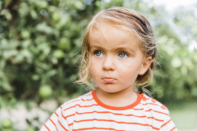 Cute girl looking away against trees