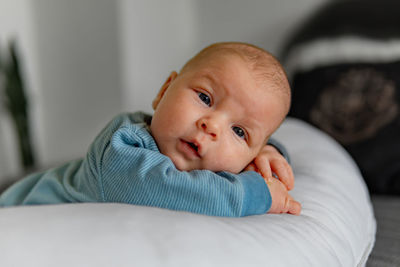 Portrait of cute baby boy lying on bed at home