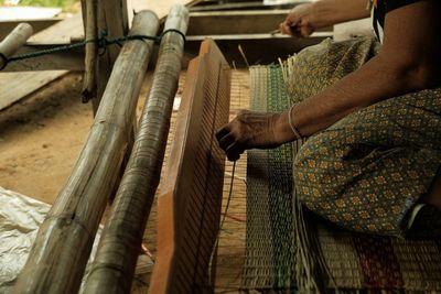 Midsection of woman weaving at workshop