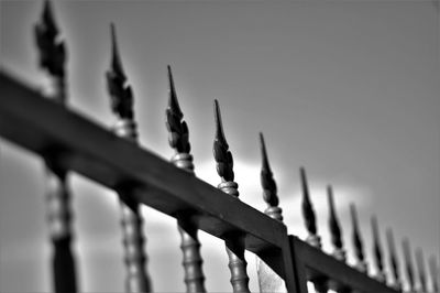 Low angle view of metal fence against sky