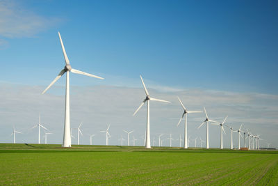 Windmills on field against clear blue sky