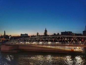 Illuminated bridge over river against sky in city