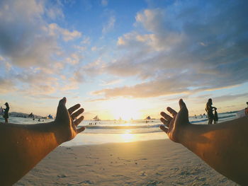 Cropped hand of person gesturing at beach