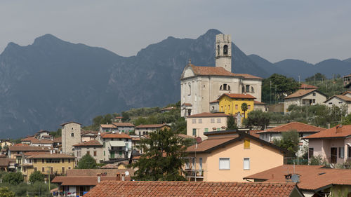 Houses in town by mountains against sky