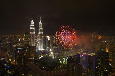 Firework display over illuminated buildings in city at night