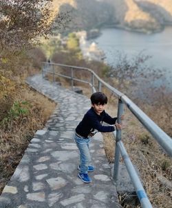 Full length of boy standing by railing