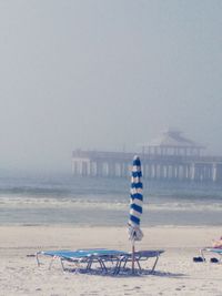 Deck chairs on beach against sky