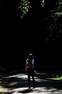Rear view of girl walking on road in forest