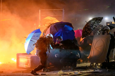 Rear view of people on wet illuminated city at night