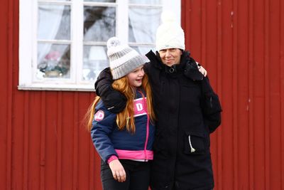 Mother and daughter standing by house during winter