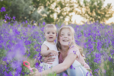 Two blond sisters in flowers at sunset