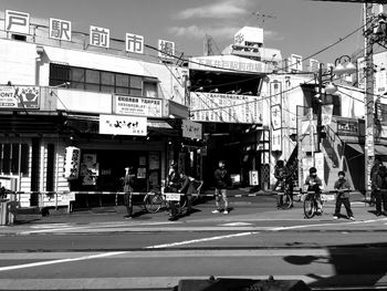 People on street by buildings in market during sunny day