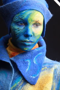 Close-up of young woman with painted face against black background