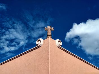 Low angle view of cross and building against blue sky