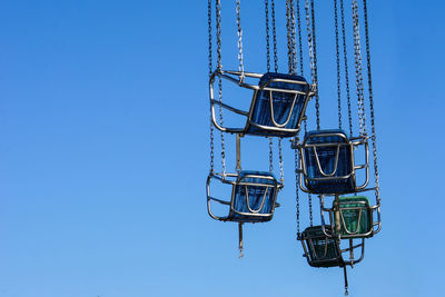 Empty seats of chain swing ride against clear sky