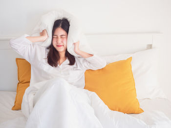 Young woman sitting on bed at home