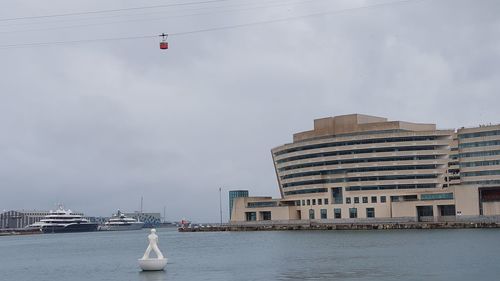 Modern buildings by sea against sky in city