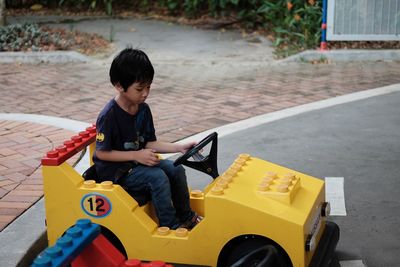 Full length of boy sitting at toy car