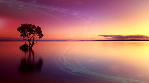 Scenic view of lake against sky at sunset